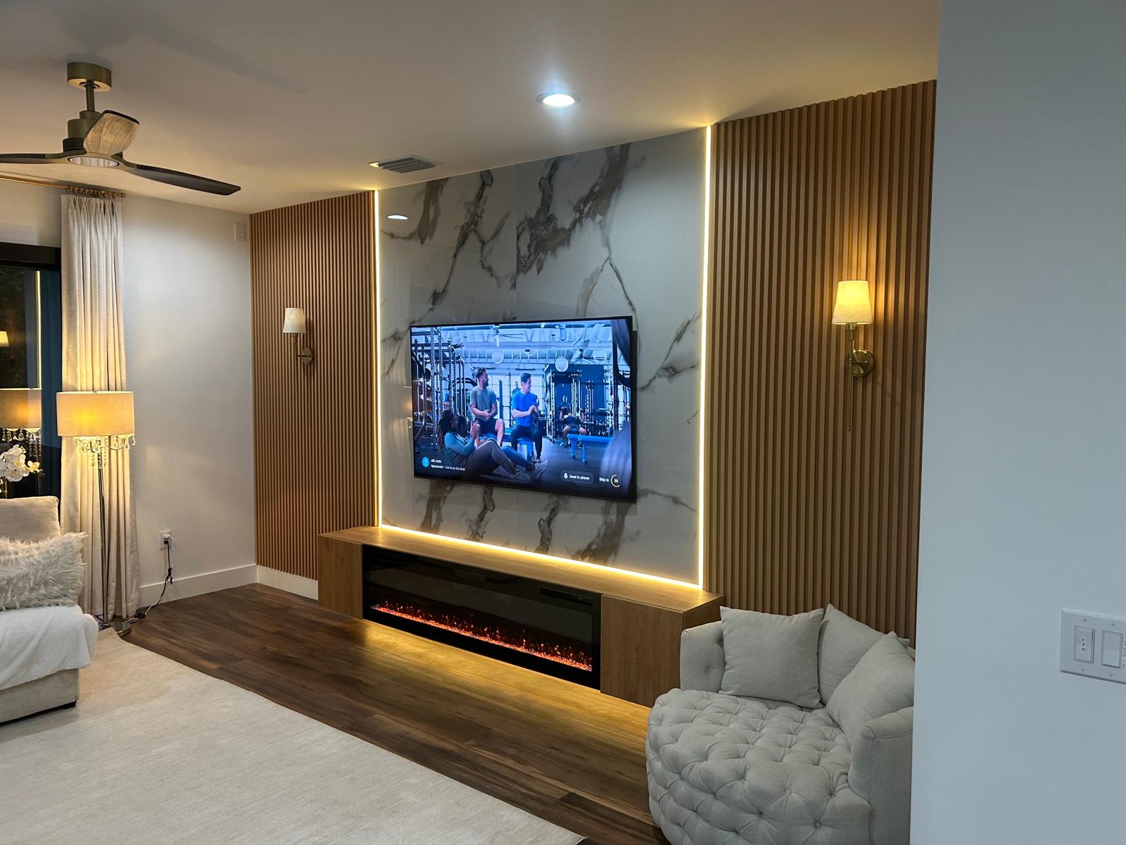 Marble media wall with lit wood slats, brass sconces and a floating fireplace console