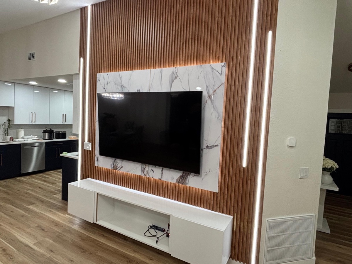 Marble TV panel on walnut slats with LED strips and a floating console